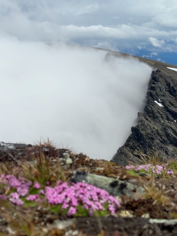 The clouds are born from the still snowy side of the mountain